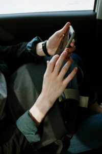 A man interacts with his smartphone while seated in a car, capturing modern transportation and lifestyle.