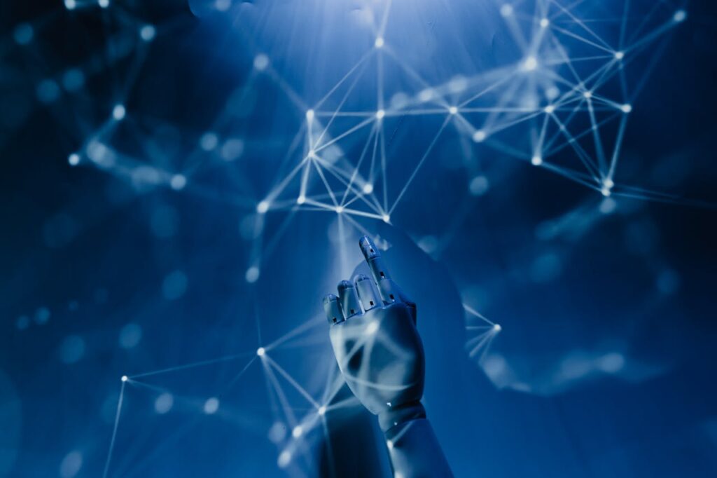 pexels-photo-8386440 A robotic hand reaching into a digital network on a blue background, symbolizing AI technology.